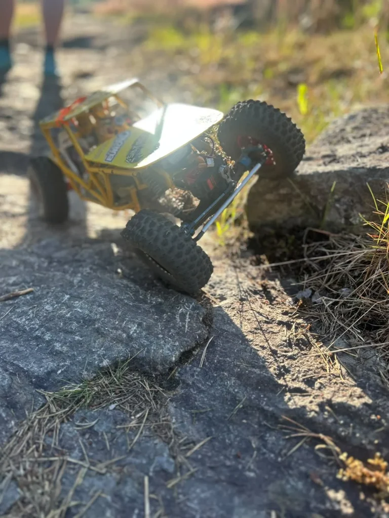 Keltainen putkirunkoinen RC-crawler kalliolla vastavalossa