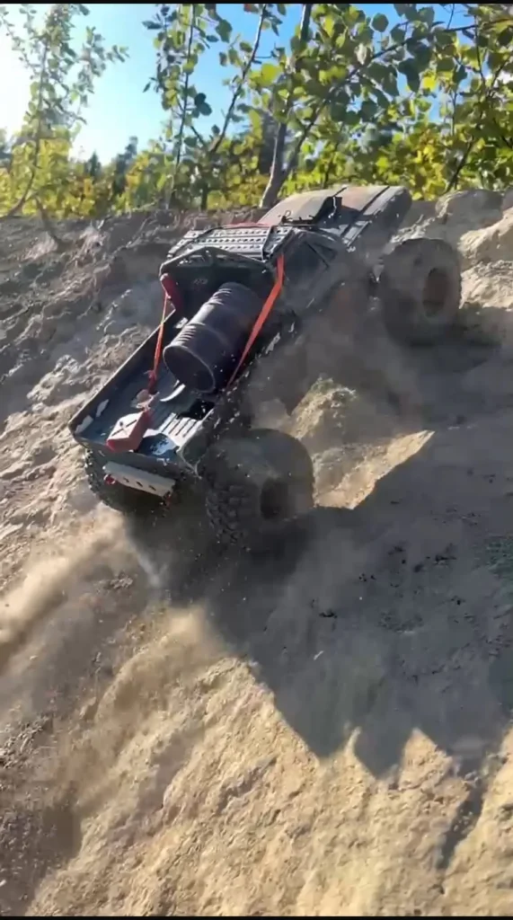 Musta RC-crawler jyrkässä hiekkatörmässä