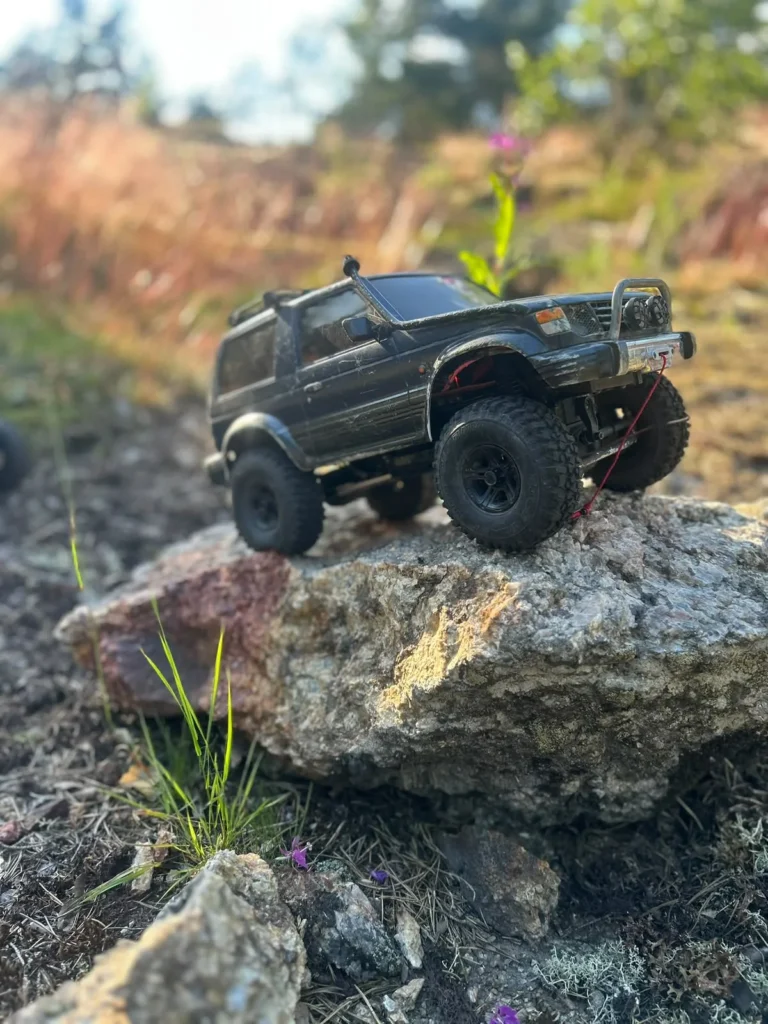 Musta Pajero-crawler sammaleisella kalliolla