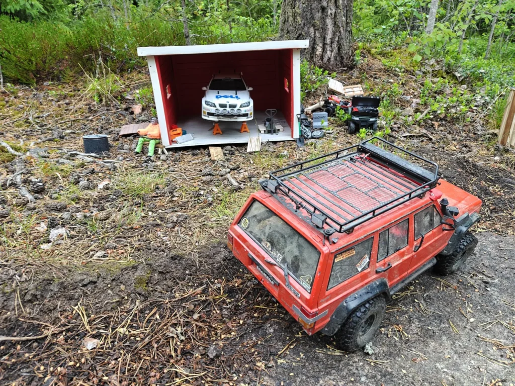 Punainen Cherokee-crawler ja pienoisautotalli metsässä