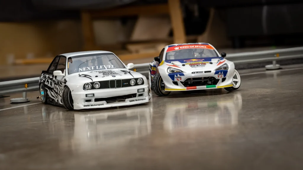 Valkoinen BMW-korinen ja kilpamaalattu RC-drift-auto vierekkäin