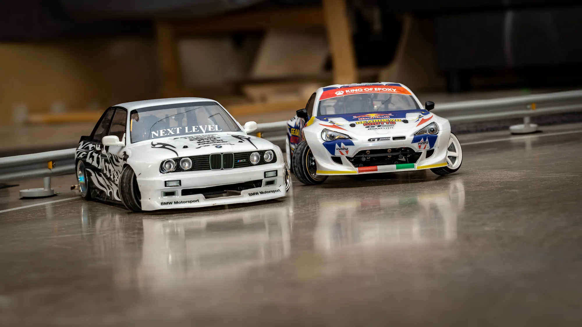 Valkoinen BMW-korinen ja kilpamaalattu RC-drift-auto vierekkäin