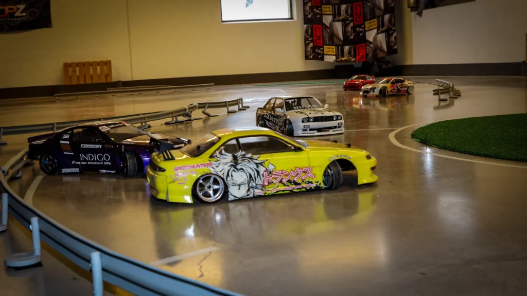Keltainen RC-drift-auto radalla, taustalla muita autoja