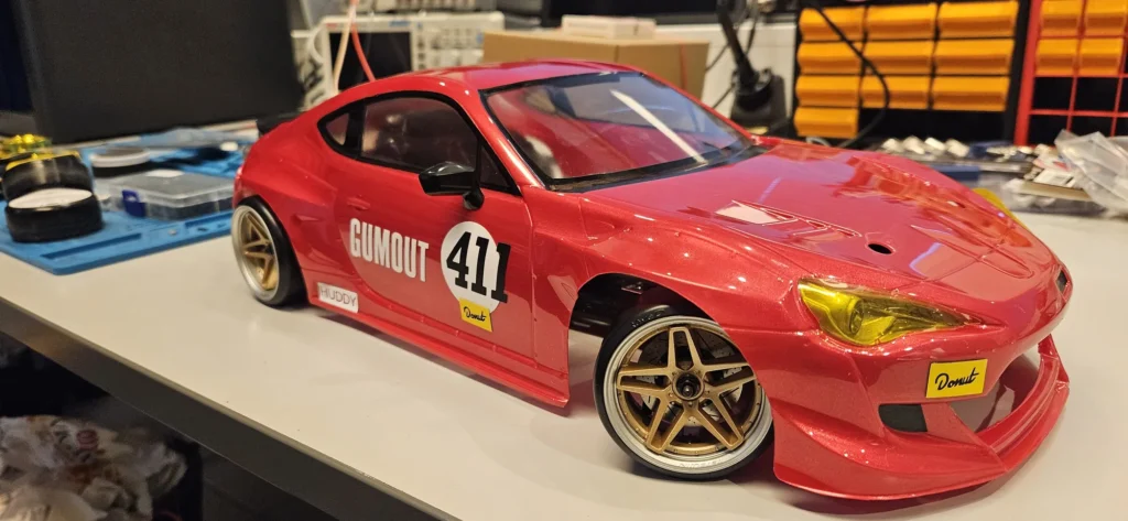 Gumout 411 -teippauksin varustettu punainen RC-drift-auto etuviistosta kuvattuna
