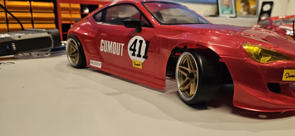 Kultaiset viisipuolaiset vanteet ja Gumout-teippaus RC-drift-auton kyljessä