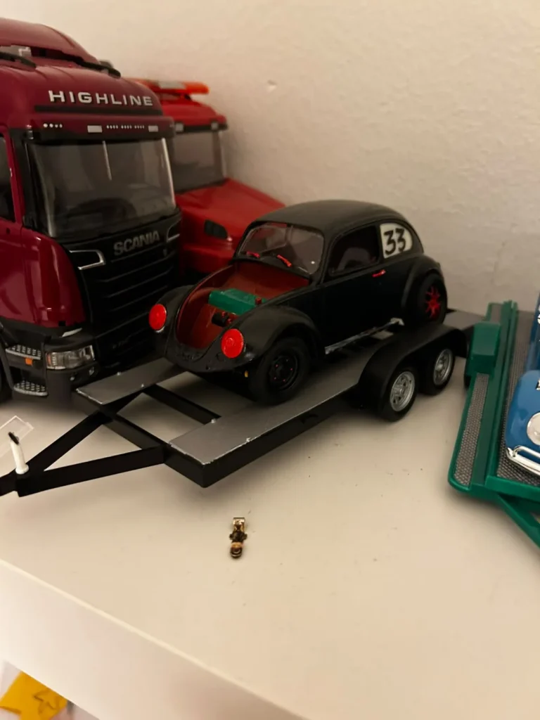 Musta RC-drift-Kupla lavettikärryllä, taustalla pienoismallirekka