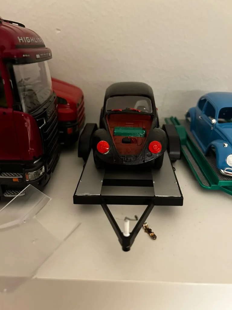 Musta RC-drift-Kupla lavettikärryllä sisätilassa, taustalla pienoismallirekkoja