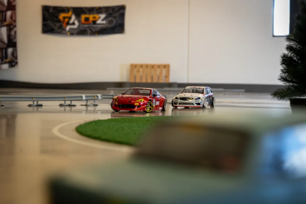 Punainen ja valkoinen RC-drift-auto radalla, taustalla seinäbanneri