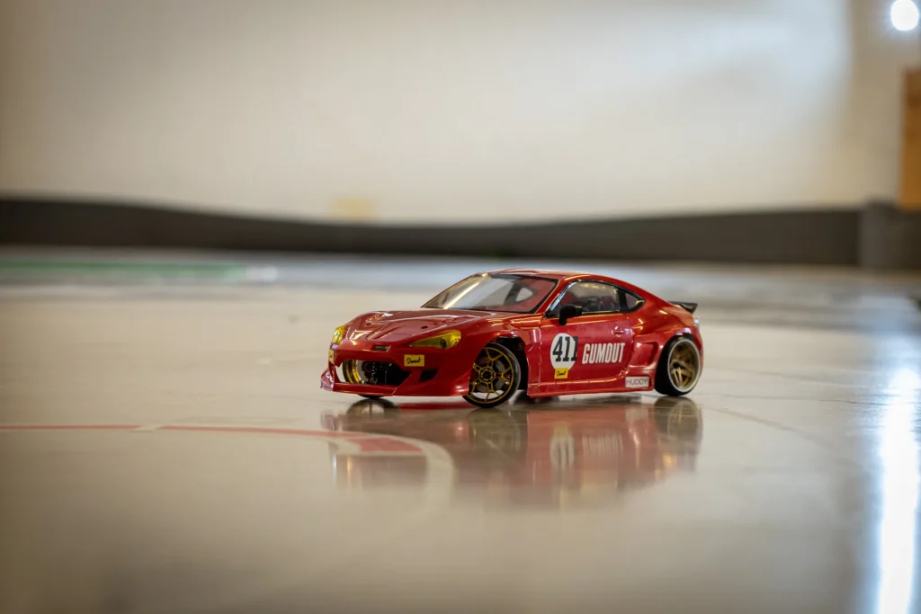 Punainen Gumout 411 -RC-drift-auto radan suoralla, heijastus lattiassa