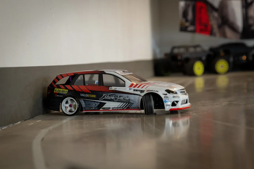 Valko-punainen kilpateippauksin varustettu RC-drift-auto radan reunalla